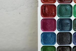 parte de la paleta blanca con acuarelas sobre fondo borroso claro, foto horizontal. tonos azules, verdes y rojos, pinturas coloridas para hacer artes y obras maestras