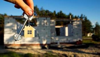 Hand with the key to the future house on the background of a construction site and walls made of porous concrete block. Building a home, moving to a new cottage, farm in the countryside photo