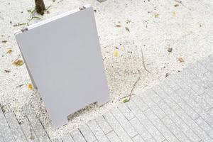 white mock up wooden sign board on concrete floor. Blank white sign outside in daytime. photo