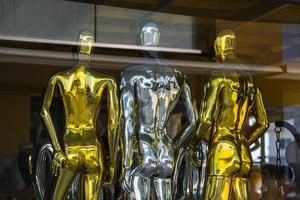 Close-up of shiny silver and gold mannequins in a shop window photo