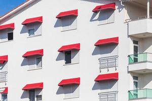 un edificio residencial blanco con ventanas idénticas con una visera roja. patrón de fachada foto