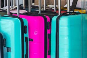 Bright  pink, green rows of suitcases with extended handles and different sizes are on sale in front of the store photo