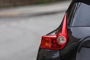 primer plano de la luz trasera de la lámpara de xenón del coche negro moderno, el parachoques, la tapa del maletero trasero. exterior de un coche moderno foto