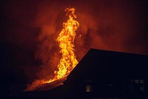 casa en llamas por la noche. fuego fuerte en un pequeño pueblo foto