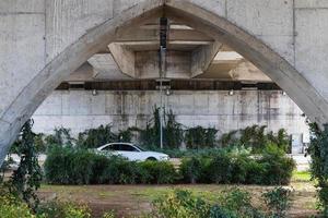 a white car moves quickly under a bridge support photo