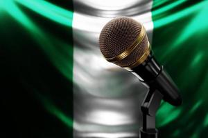 micrófono en el fondo de la bandera nacional de nigeria, ilustración 3d realista. premio de música, karaoke, radio y equipo de sonido de estudio de grabación foto