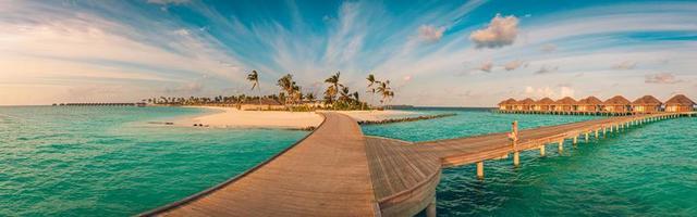 increíble panorama de la puesta de sol en maldivas. Villas de resort de lujo marino con luces LED suaves bajo un cielo de colores. hermoso cielo crepuscular y nubes de colores. hermoso fondo de playa para vacaciones vacaciones foto