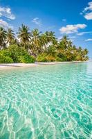 hermosa playa tropical, tranquila laguna de mar turquesa, arena blanca, palmeras, contra el cielo azul con nubes en un día soleado de verano. fondo paisajístico perfecto para unas vacaciones relajantes, isla de maldivas. foto