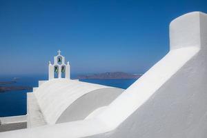 Santorini blue dome and whitewashed structures on light blue sky. Fantastic summer travel landscape, idyllic street view over blue sea photo