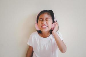 Portrait of young happy asian girl enjoying music with headphones on white background.  Enjoy the sound concept. photo