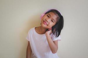 Portrait of young happy asian girl enjoying music with headphones on white background.  Enjoy the sound concept. photo