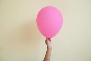 cerrar el niño de la mano sosteniendo el globo rosa aislado sobre fondo blanco. foto