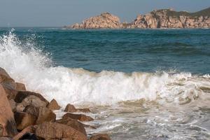 la ola choca contra las rocas de una costa foto