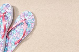 Summer background with fashion flip flops on beach sand background. Copy space. Top view photo