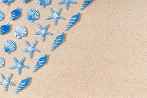 Summer background with blue seashell pattern on beach sand background. Copy space. Top view photo