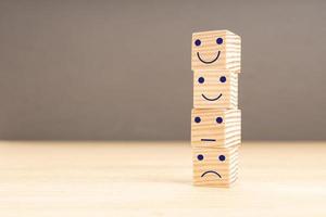 Customer service evaluation and satisfaction survey concept. Face emoticon on stacked wooden blocks. Copy space photo