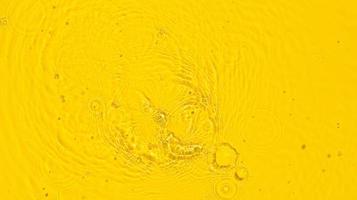 fondo abstracto de verano. textura superficial de agua clara amarilla transparente con ondas, salpicaduras y burbujas. vista superior foto