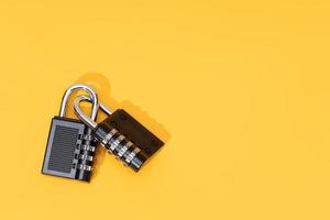 Two padlocks linked together isolated on yellow background. Copy space. Top view photo