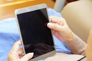 Asian senior or elderly old lady woman is using or playing tablet enjoying, happy. Healthcare, medical and technology concept. photo