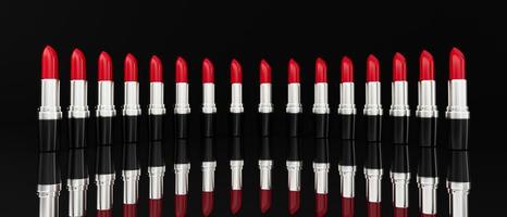 Red lipsticks marching in a row on a black background. 3d illustration photo
