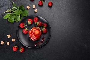 tortitas de requesón con fresas en rodajas y mermelada de fresa en un plato sobre un fondo de hormigón foto