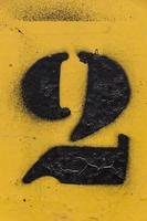 plantilla número negro pintado sobre fondo amarillo, número dos, número 2 foto