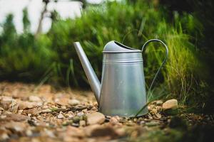 Metal watering can be laying on the stone floor, in the garden, at evening time. soft focus.shallow focus effect. photo