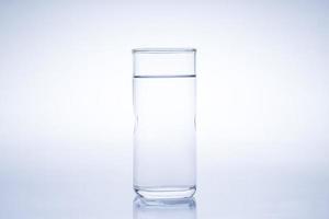 el cubo de hielo cayó en el vaso de agua. agua salpicada del cristal transparente. concepto fresco foto