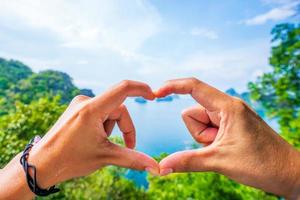 forma de corazón hecha con manos de hombre y mujer concepto de símbolo de amor, fondo borroso, isla phi phi, en la provincia de krabi foto