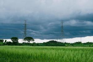 black clouds before the rain and high voltage poles near rice fields photo