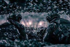 vista trasera de soldados en el campo de batalla, base militar, misión en curso, en el bosque por la noche foto