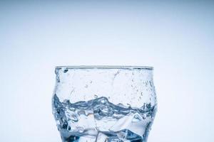 cubo de hielo cayó en el vaso de agua. agua salpicada del cristal transparente. concepto fresco