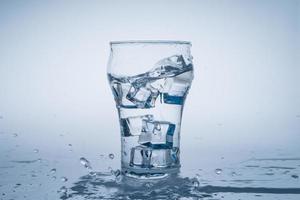 Ice cube fell into the glass of water. Water splashed from the clear glass. Fresh concept photo