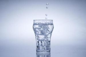 Ice cube fell into the glass of water. Water splashed from the clear glass. Fresh concept photo