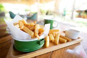 patatas fritas en un recipiente de esmalte verde, sobre una mesa de madera tailandesa foto