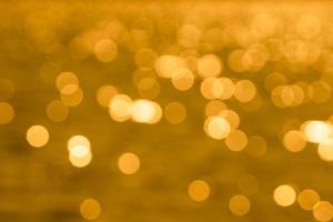 Bokeh light from reflection of golden water surface in the evening sunset photo