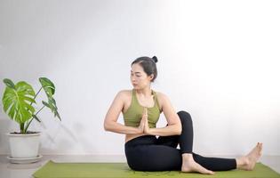 mujer haciendo yoga en la alfombra de yoga verde para meditar y hacer ejercicio en el hogar. foto