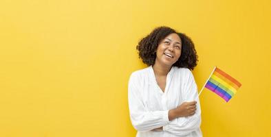 retrato de una mujer africana ondeando la bandera del arco iris lgbtq por salir del armario en el mes del orgullo para promover la igualdad en el matrimonio y las diferencias del concepto de homosexualidad y discriminación foto