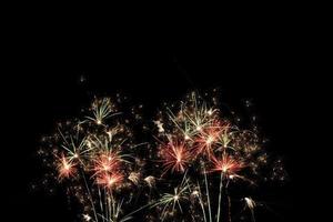 Festive fireworks display light up over night sky at the beach. Colorful firework celebration on dark background. photo