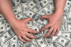 Hands on the background of American dollars. A man is trying to take himself a big pile of money from hundred-dollar bills photo