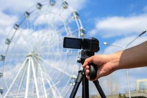 Video shooting on the camera of a ferris wheel in a park on the background of a cloudy sky photo