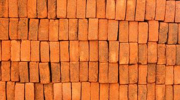 Beautiful pile of red bricks in the same order in each row. Closeup of red clay bricks stacked in piles for building construction. photo