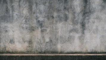 The old cement wall was weathered, the surface was scratched, the surface was scratched and damaged. For a mysterious retro-conservative background. photo