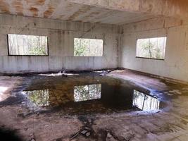 edificio abandonado habitación abandonada con paredes agrietadas y pintura descascarada hay agua dentro del horror. foto