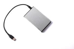 Gray external hard disk with black USB cable on white background. photo