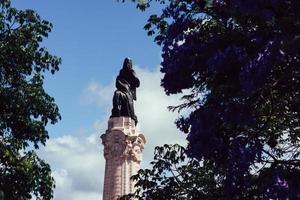 Jacaranda tree on foreground with Marques do Pombal statue with lion and square in Lisbon, Portugal photo