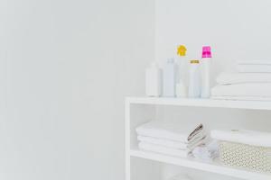 Stack of white soft towels with soft conditioner liquid. White background with copy space for your information. Cleanliness concept. Natural light photo