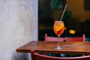 bebida sabrosa mezclada con hielo y naranja. cóctel aperol spiritz sobre mesa de madera. bebida de restaurante fiesta de verano. bebida que contiene alcohol. foto