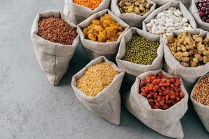 Dieting, nutrition and healthy eating concept. Colorful cereals and dried fruits rich with protein in burlap sacks. Dry legumes seeds. photo