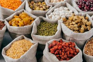 Food concept. Close up cropped shot of various kinds of natural cereals and dried fruit in sacks. Legumes in bags. Products for vegans photo